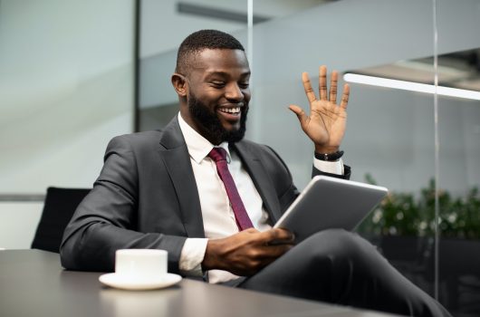 Happy black businessman having video chat, using digital tablet